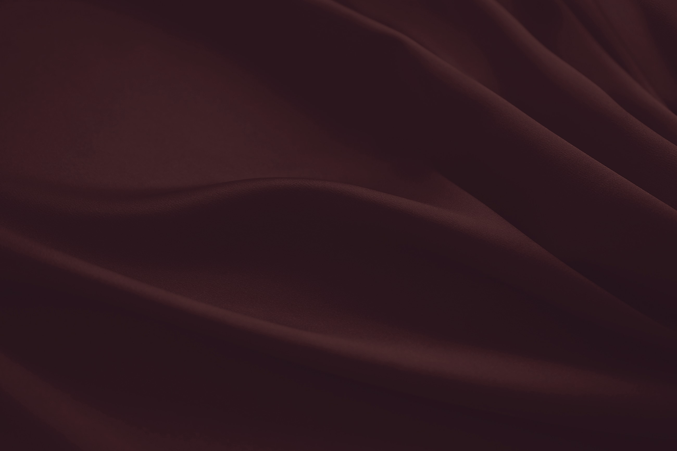 Textured burgundy fabric with gentle folds and curves.