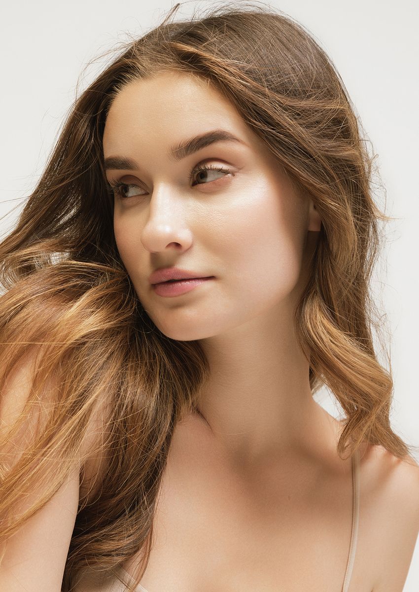Woman with long hair resting her chin on hand.