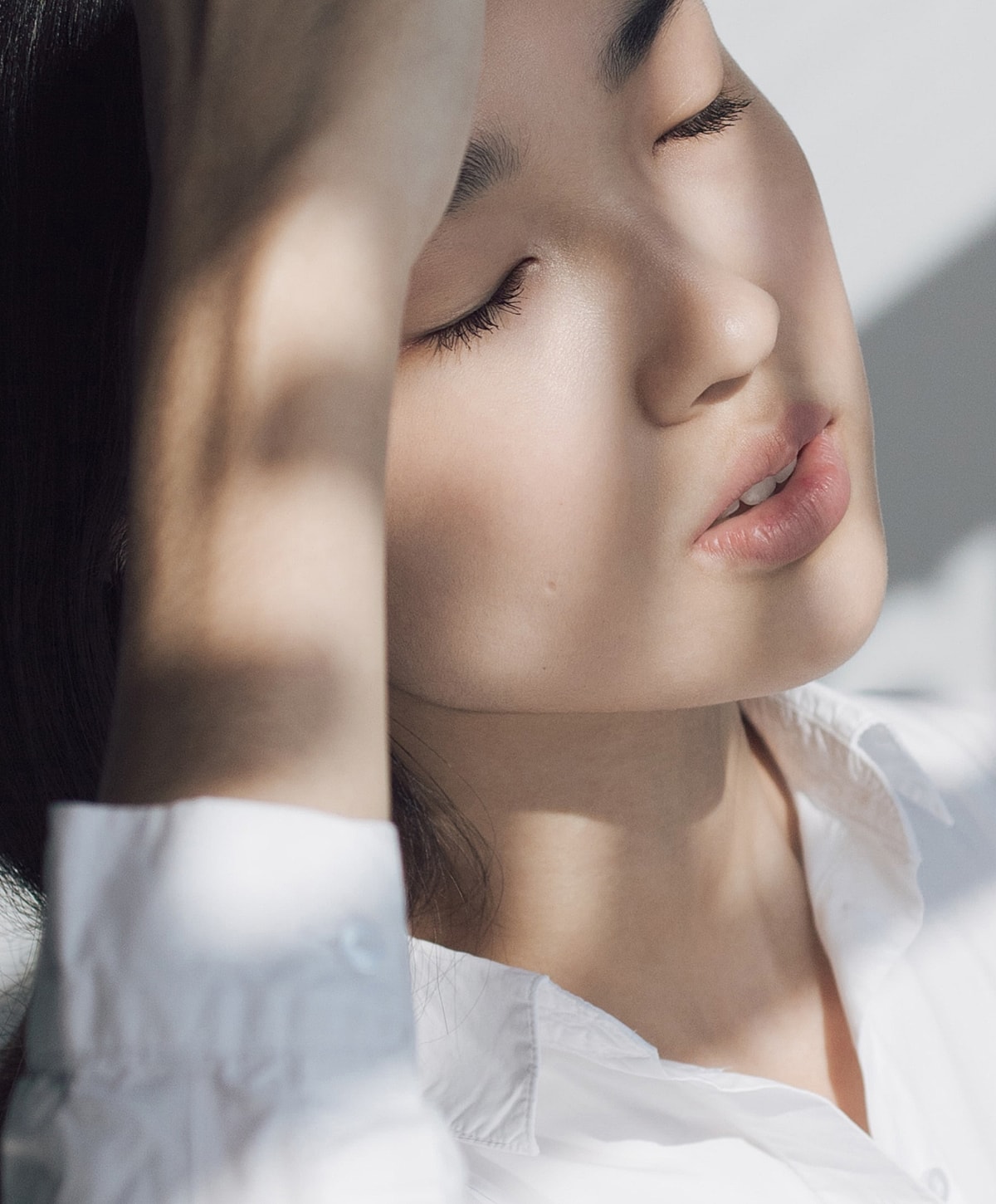 Woman with eyes closed in soft lighting.