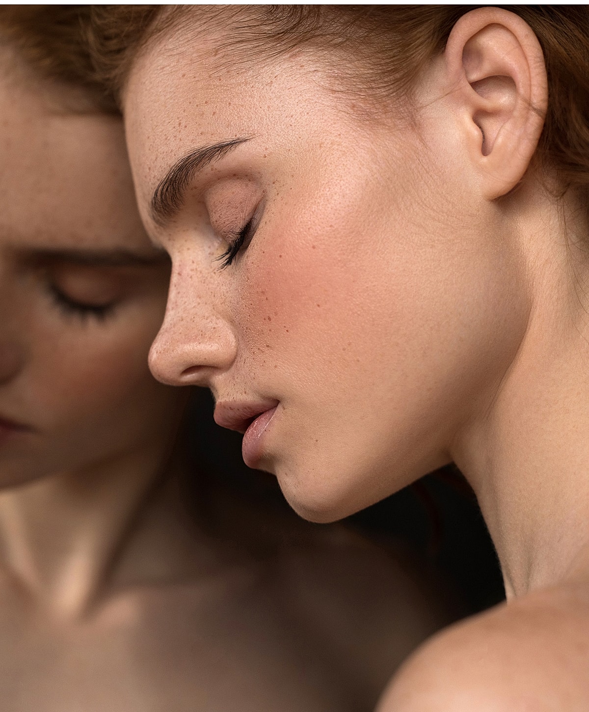 Close-up of a woman's serene profile while she leans against a mirror