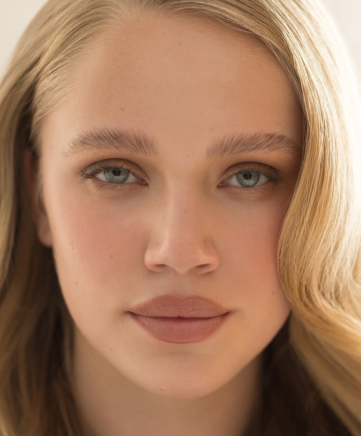 Smiling woman with blonde hair and blue eyes with natural makeup on.