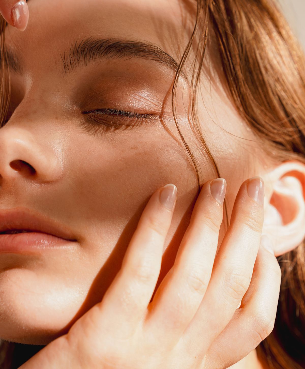 Close-up of a person’s serene face and hand.