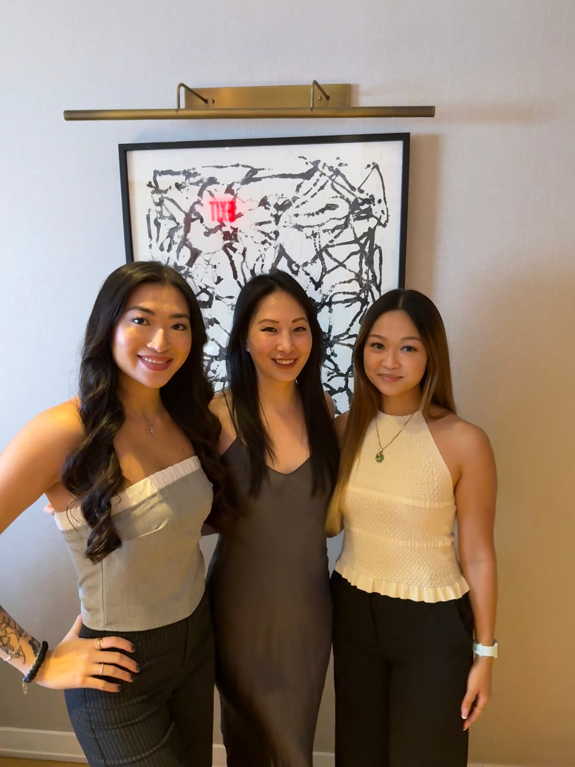 Three women posing together in stylish outfits.