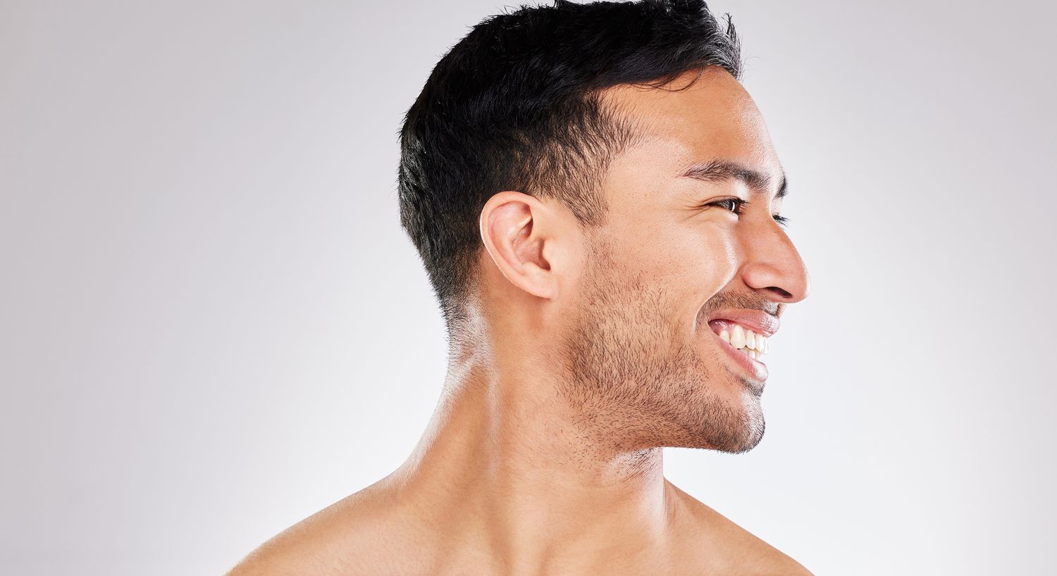 Smiling man in profile against light background.