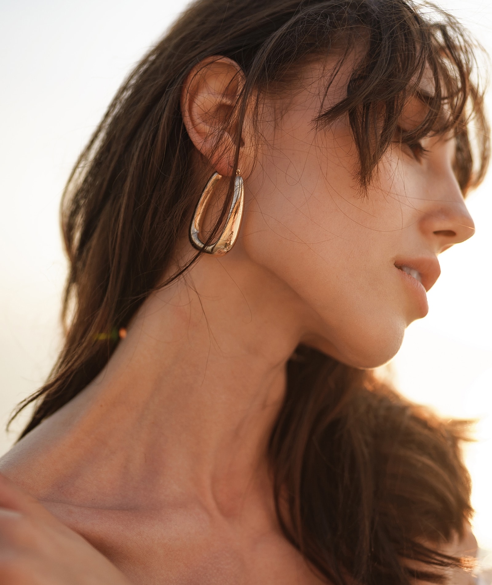 Woman with elegant earrings at sunset.