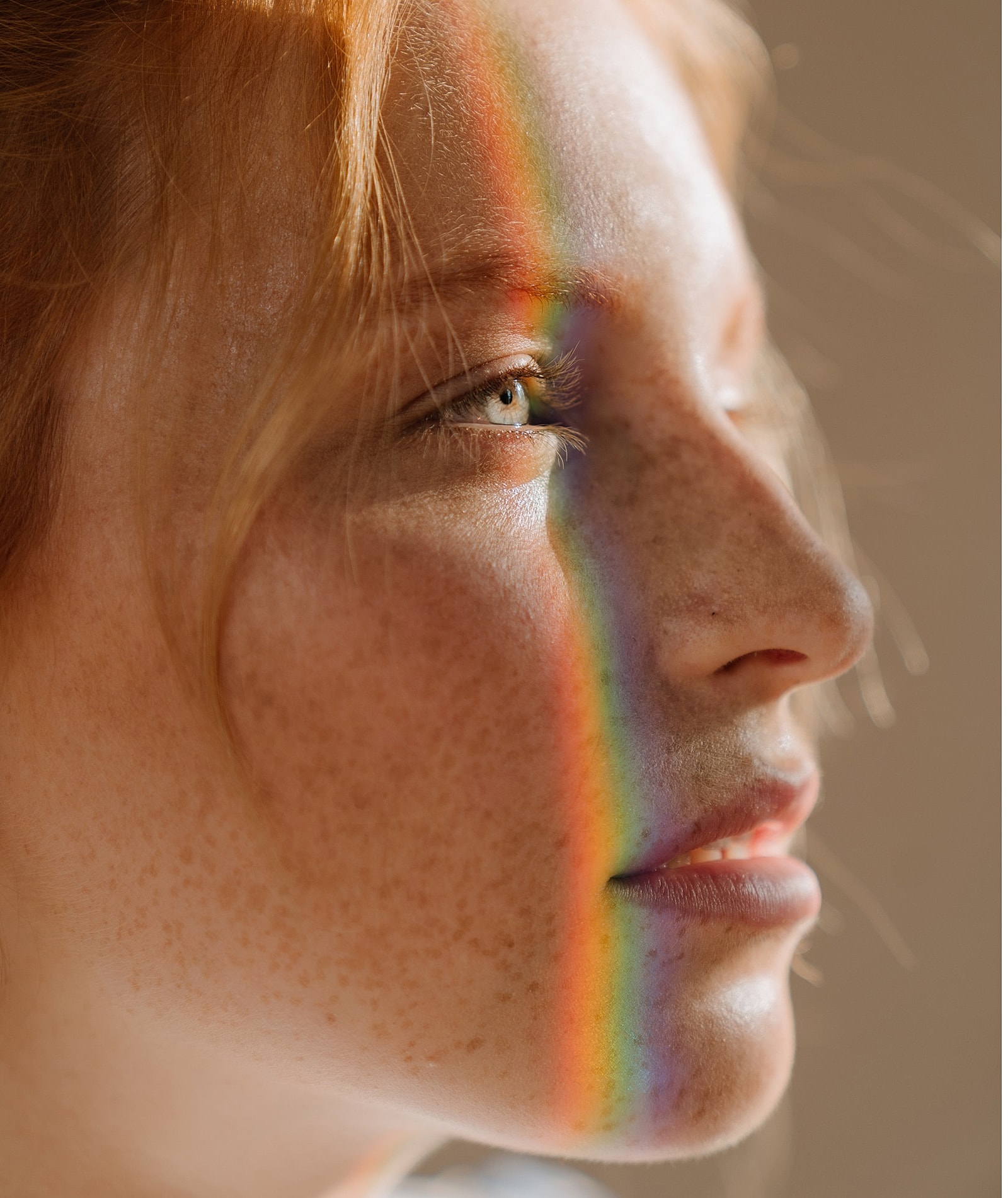 Person's face with rainbow reflection and freckles.